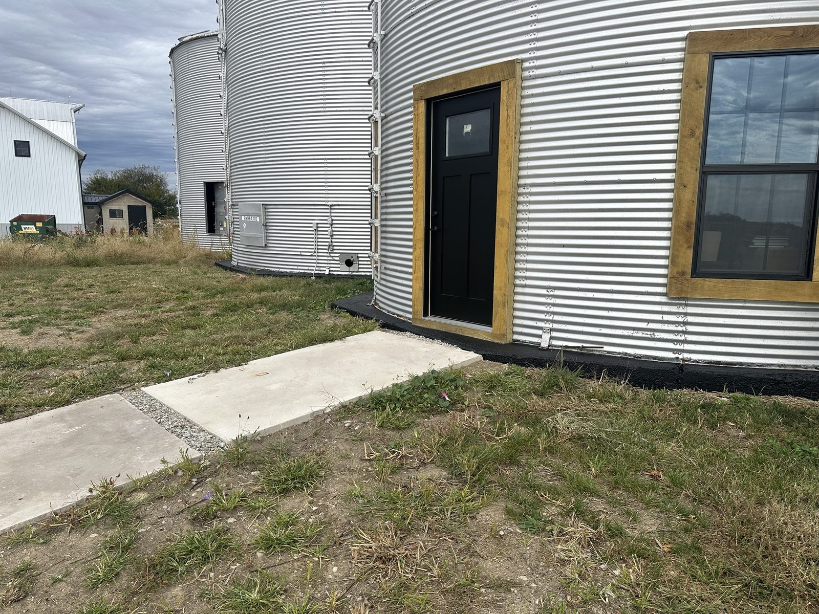 Grain bins converted to living space, with black painted foundation bands, cedar-trimmed windows and black doors