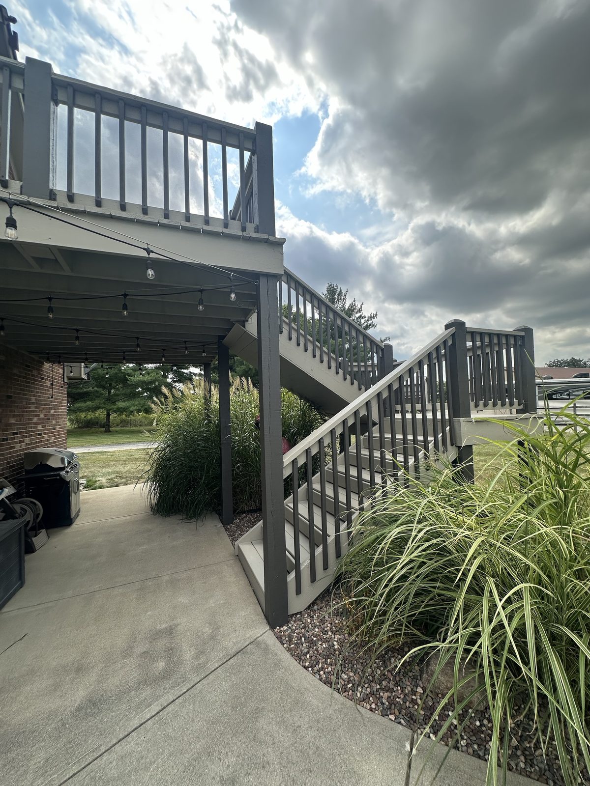 A raised deck with dark stained posts and railings over lighter stained stairs and treads
