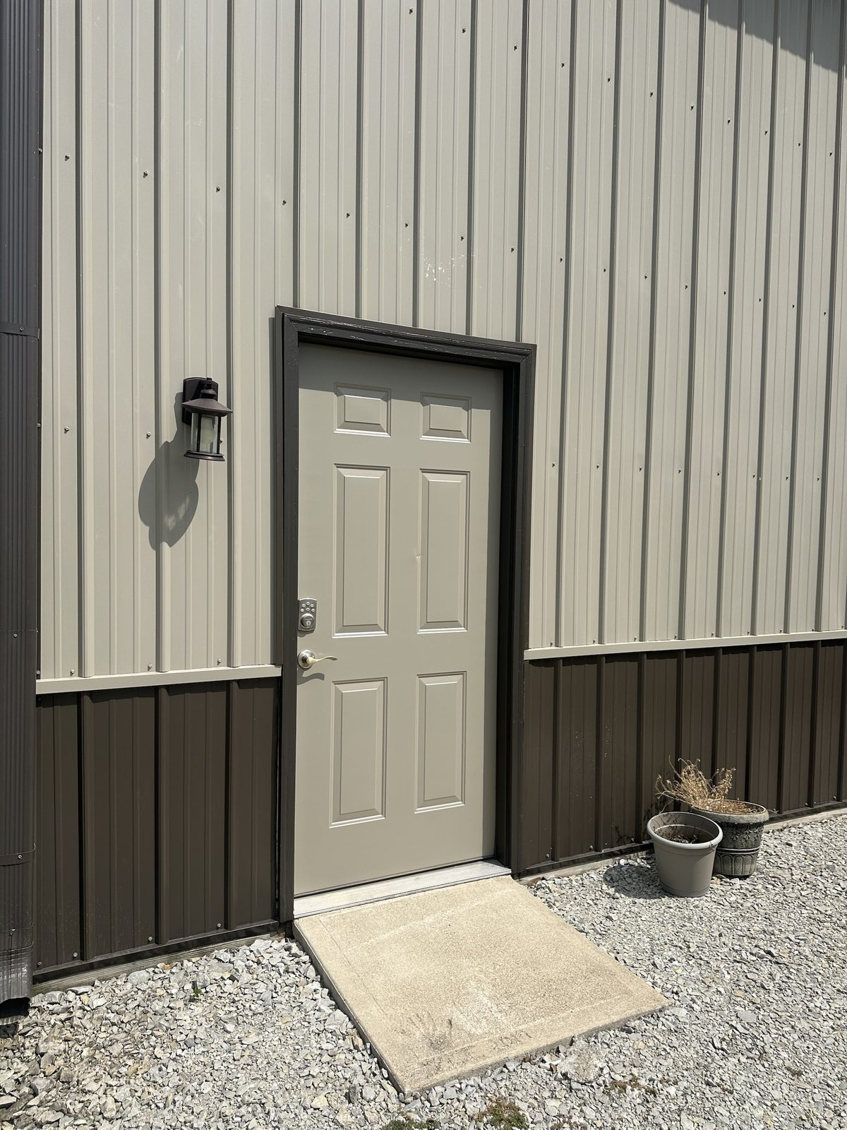 A pole barn entry door painted tan with a dark brown frame, matching the metal siding