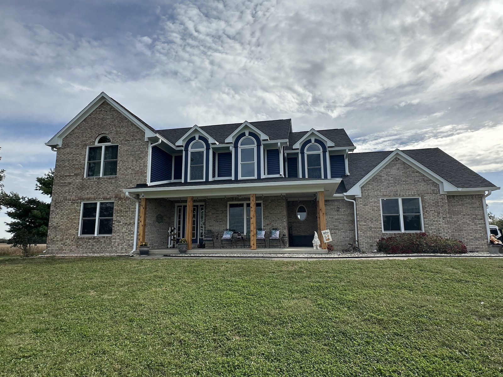 A two-story brick home with freshly painted navy dormer siding, crisp white trim and a covered front porch