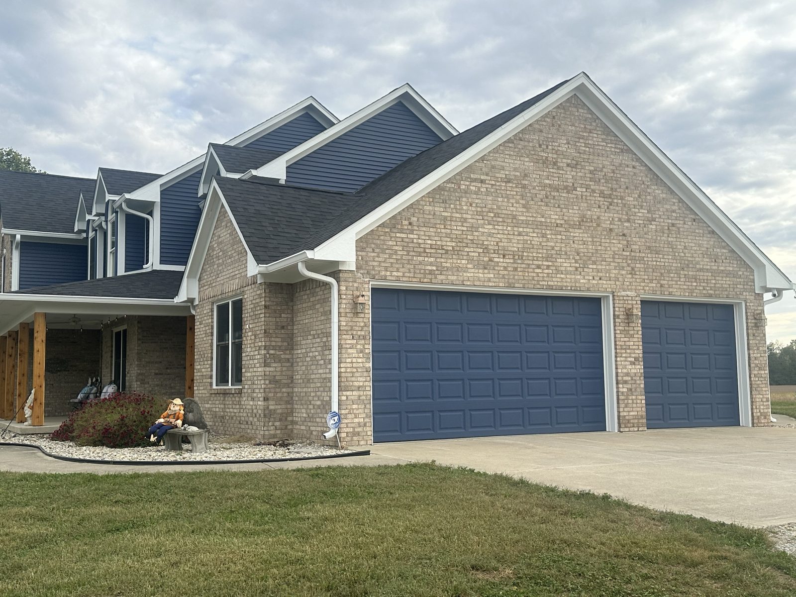 Side of a brick home showing newly painted navy garage doors and white gable trim and fascia