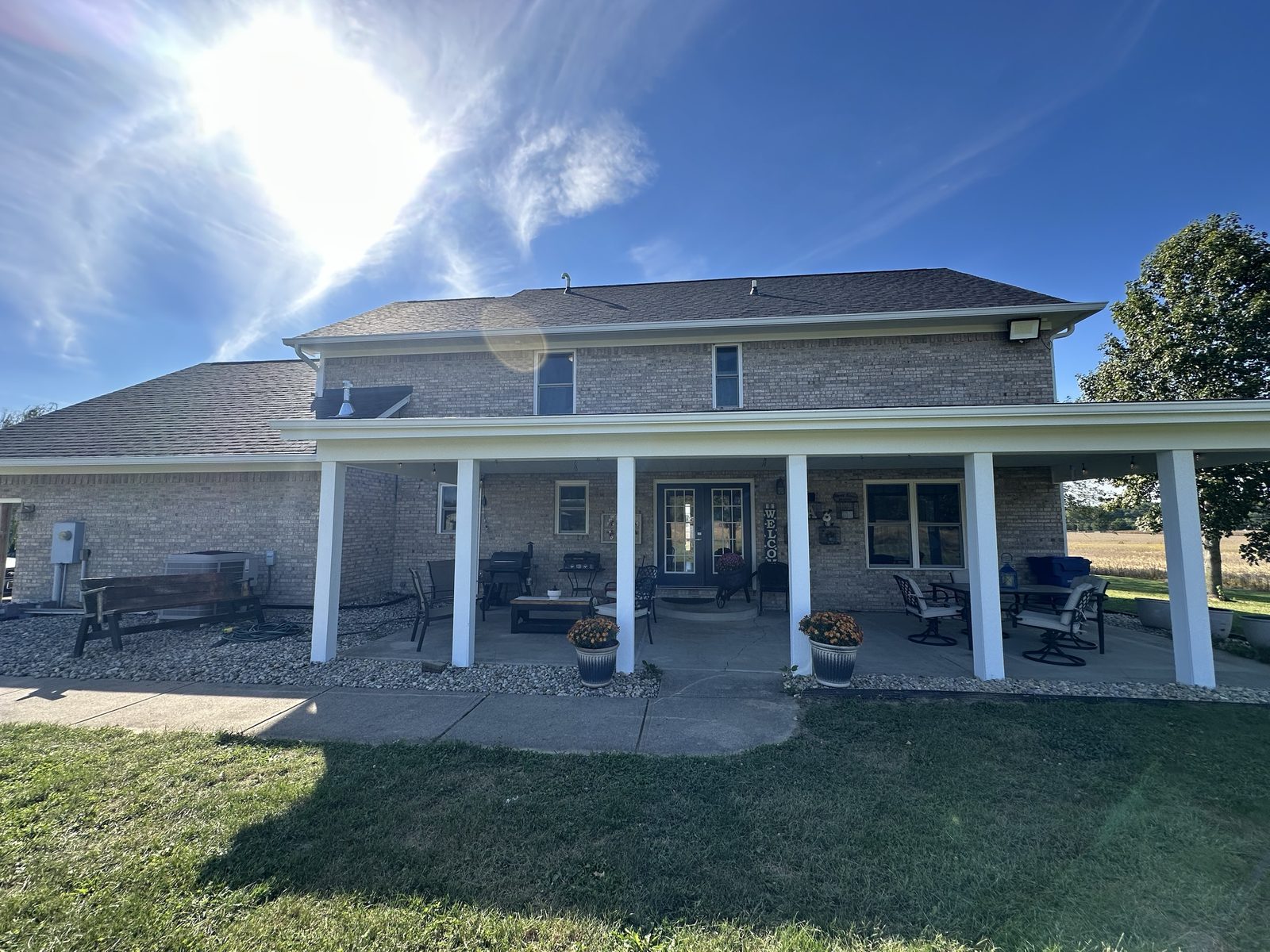 Rear of a brick home with a long covered porch, freshly painted white columns and soffits