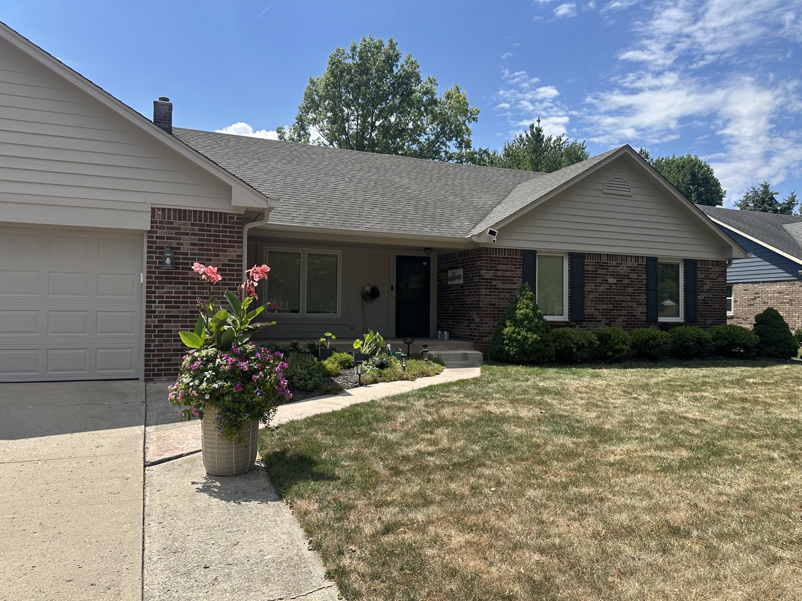 A brick ranch home with a freshly painted porch, trim and black front door