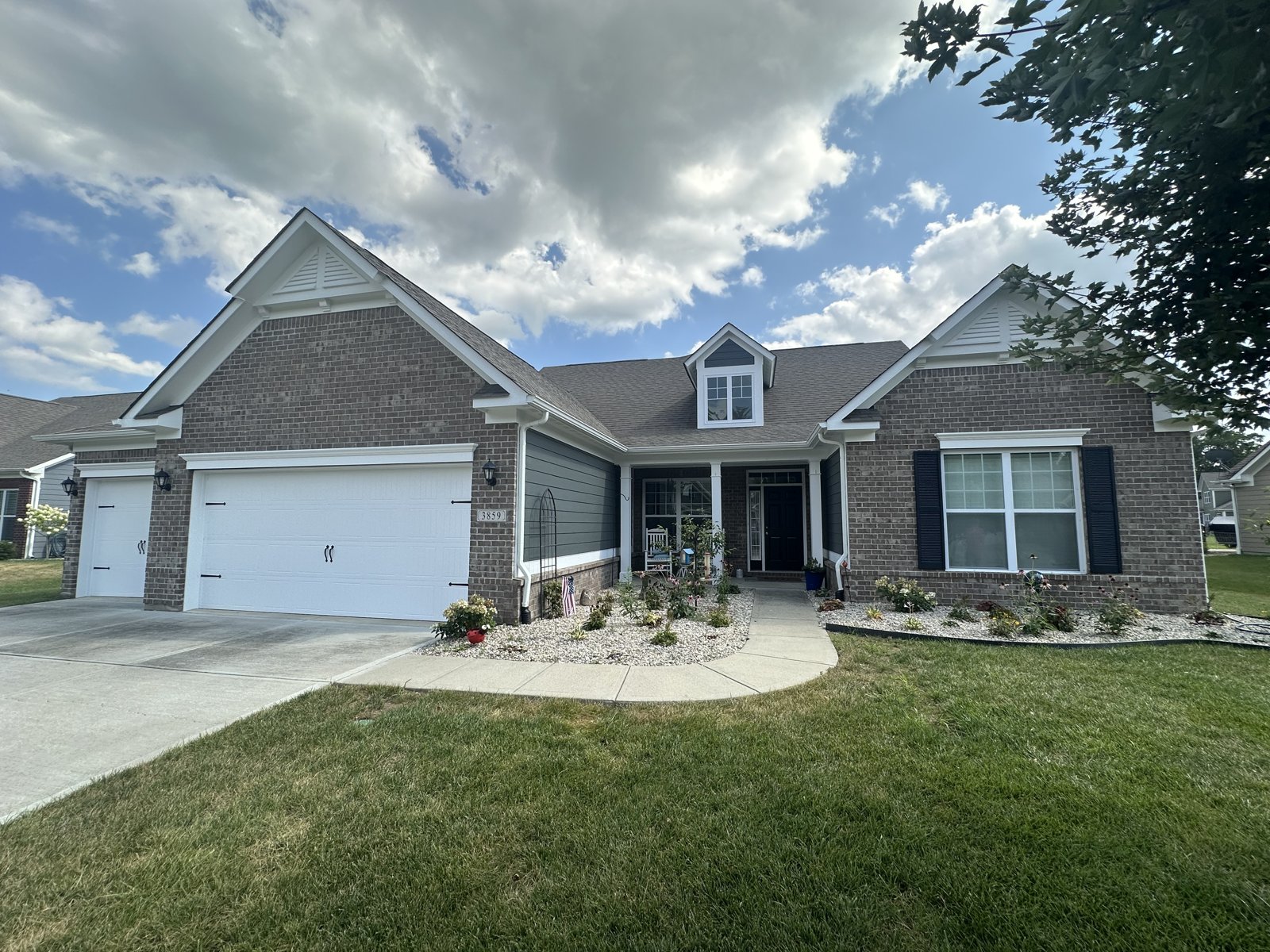A brick ranch home with gray board-and-batten accent siding, white trim and black shutters