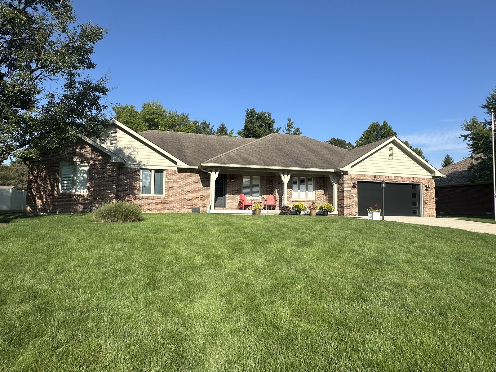 A brick ranch with a covered porch, freshly painted trim, gables and siding