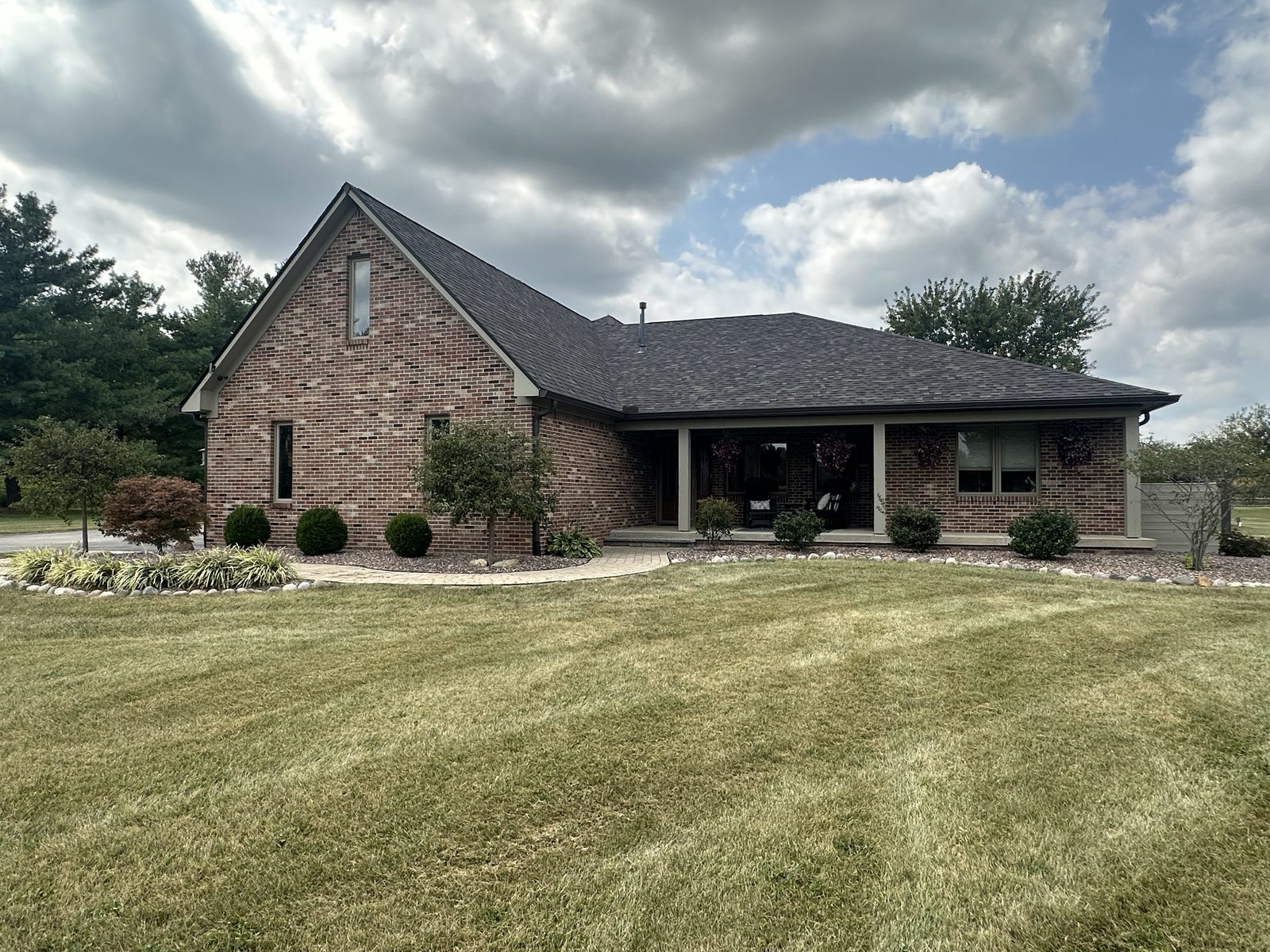 A brick ranch home with freshly painted cream trim, soffits and covered front porch