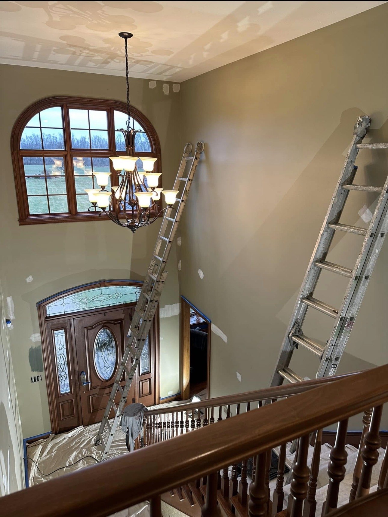 A two-story foyer with ladders set up for high wall work
