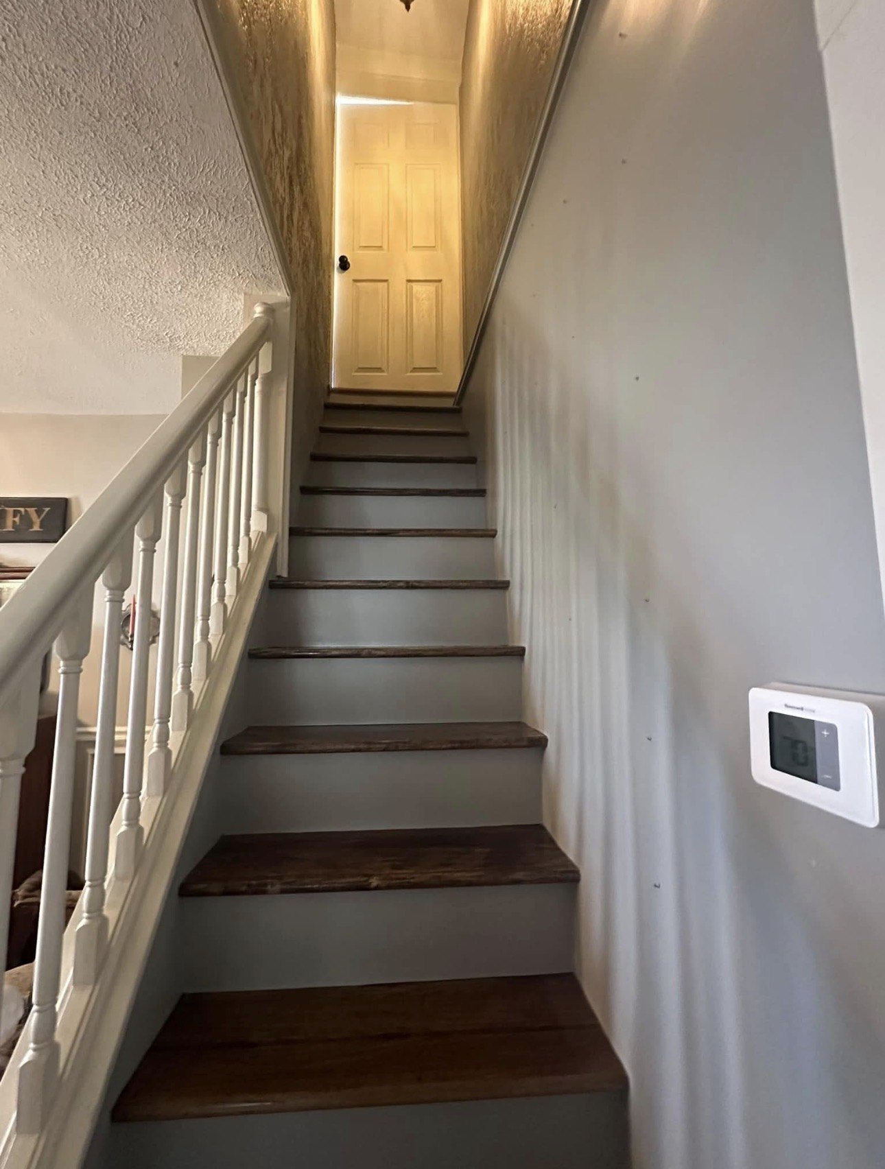 A painted stairwell with stained treads and white railing